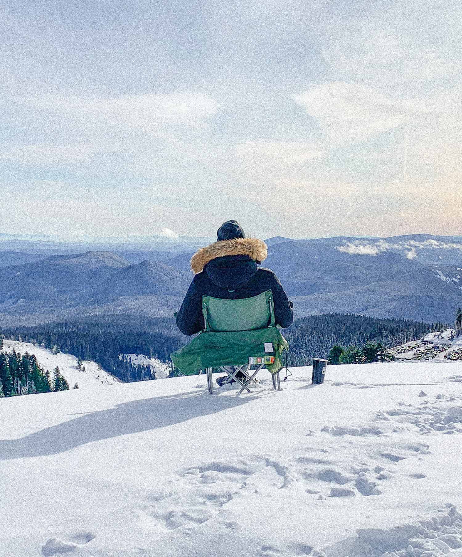 a person sitting on a chair on a snowy mountain